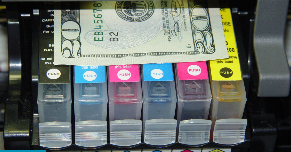 Close-up of a printer’s ink cartridges with a U.S. twenty-dollar bill placed on top.