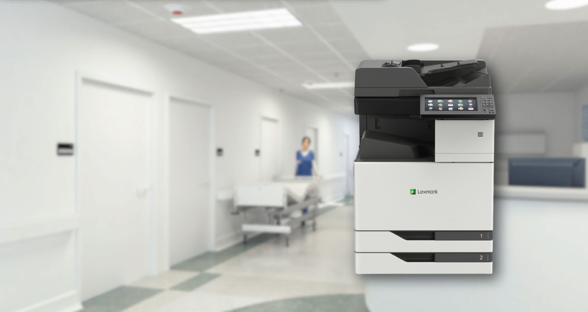 Lexmark multifunction printer placed in a clean, modern medical clinic hallway with a healthcare worker in the background.