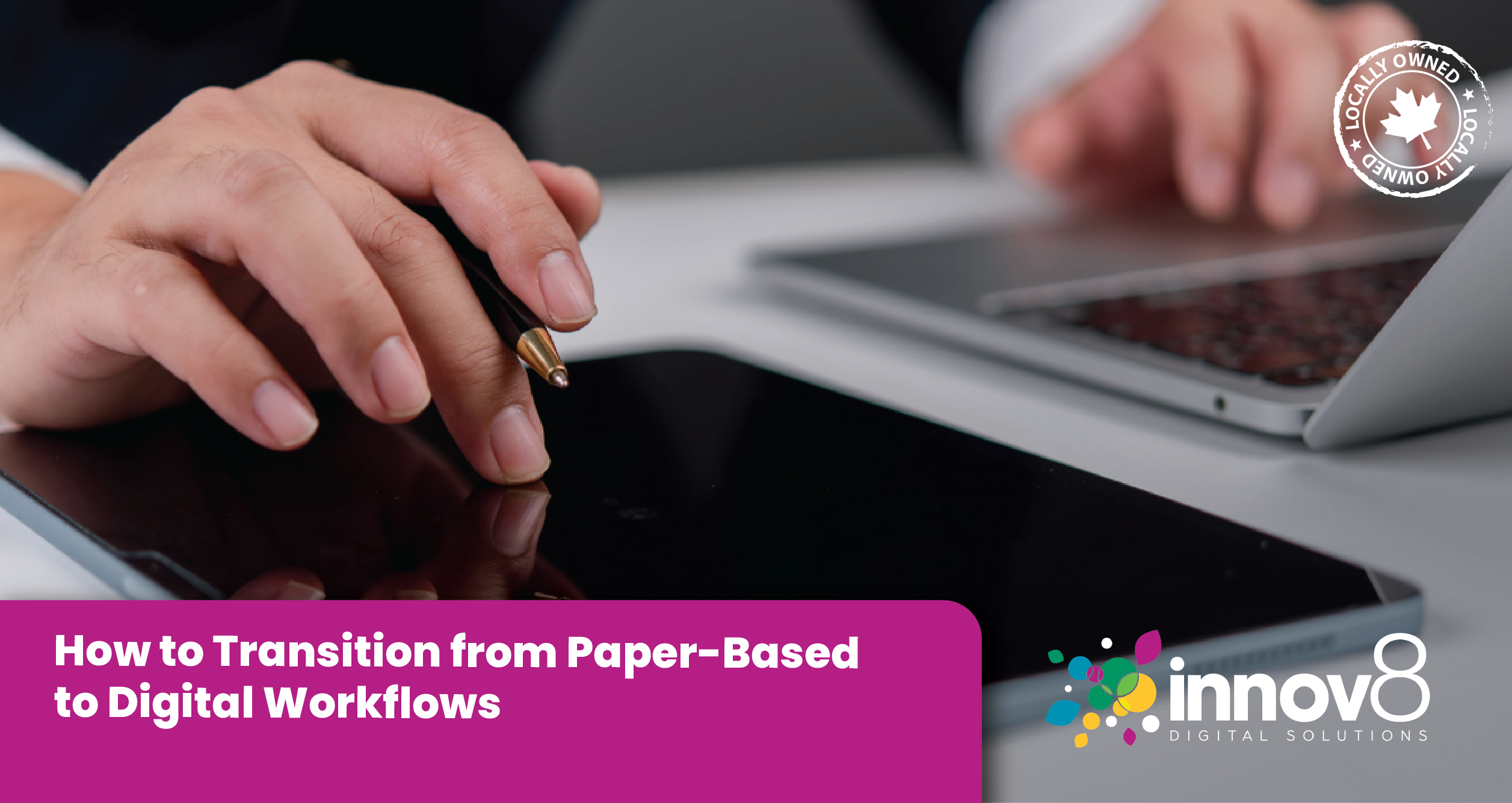 Hand holding a pen above a digital tablet, with a laptop in the background, representing modern office technology use.