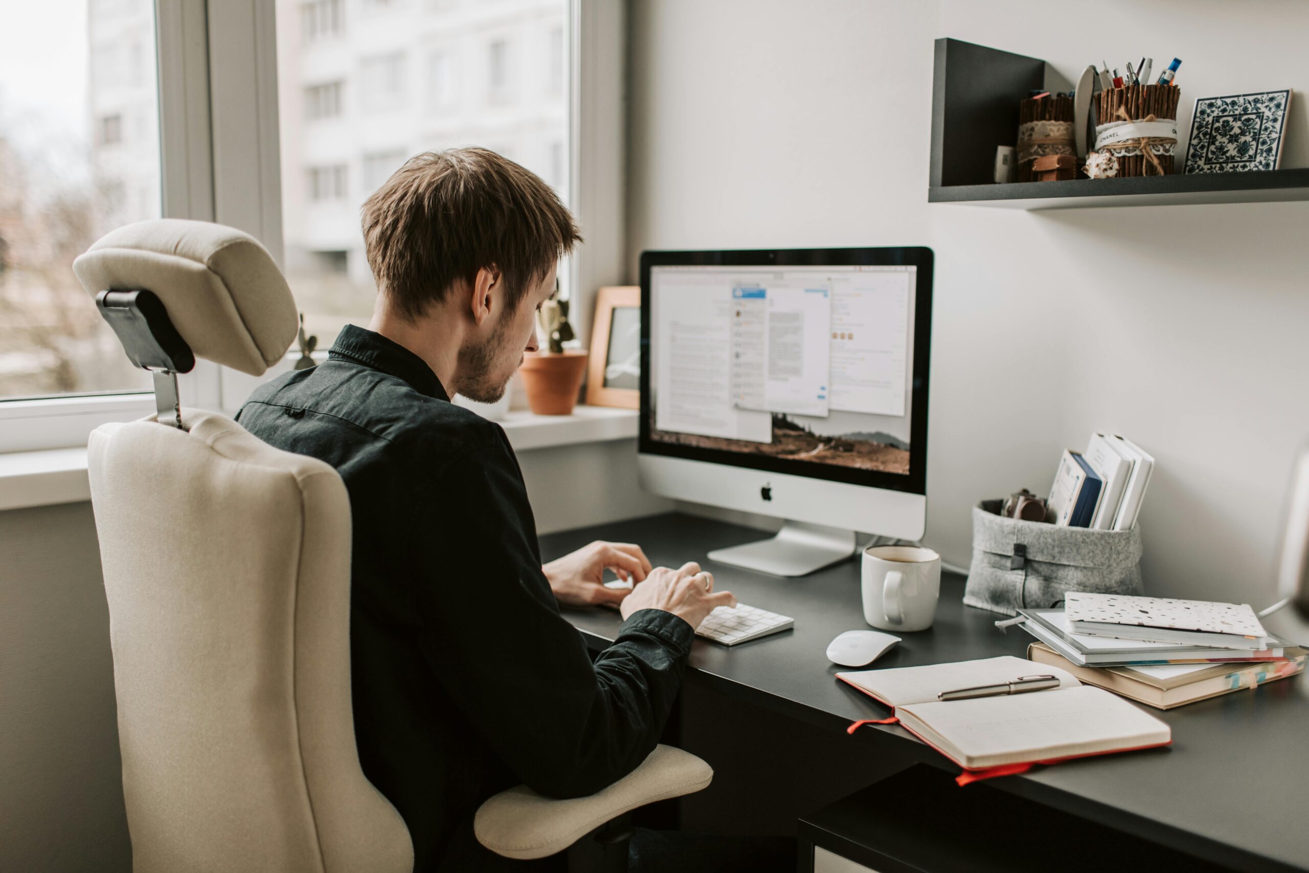 An image of a man sitting in front of a computer while typing away on a keyboard 